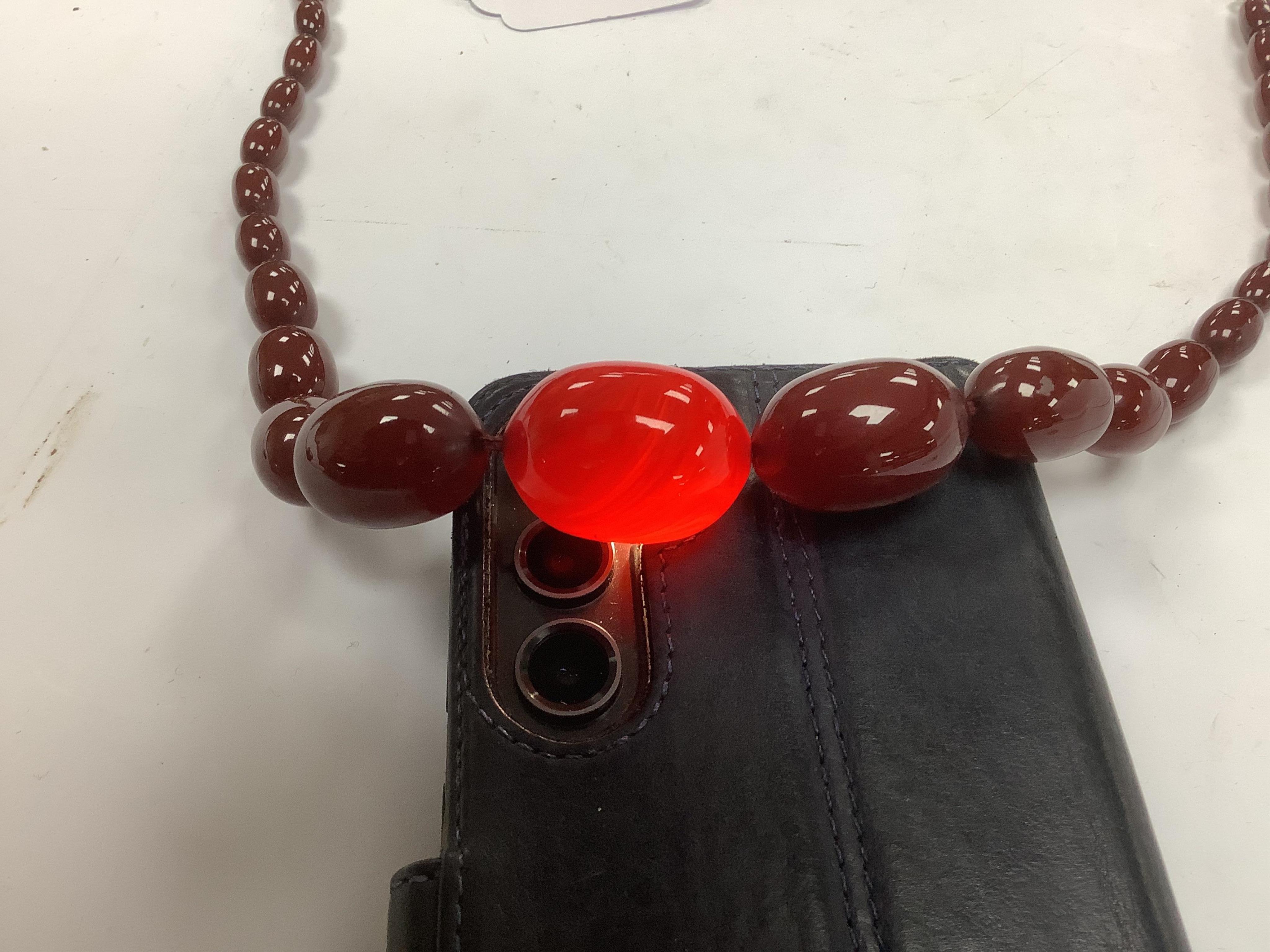 A graduated simulated cherry amber bead necklace, 43cm, gross weight 54 grams and two other necklaces including malachite. Condition - fair to good